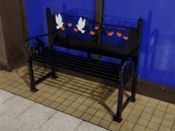 a black bench with white doves and red poppies decorating the back