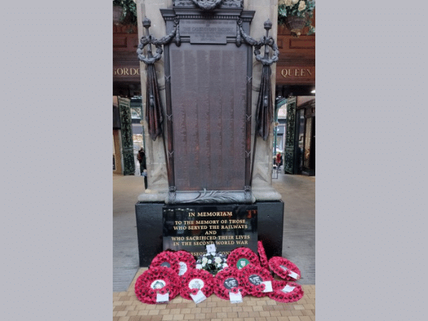 wreaths of poppies at the base of a memorial within Glasgow Central Station