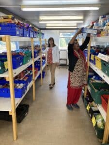 two ladies stack shelves with food at Renfrewshire Food Bank