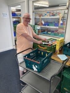 a volunteer smiles whilst filling up baskets at Renfrewshire Food bank