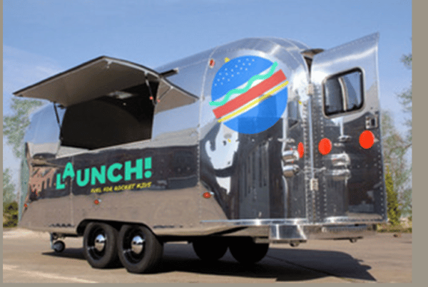 A Launch Foods food truck which is silver with the word Launch and graphic designs on the side
