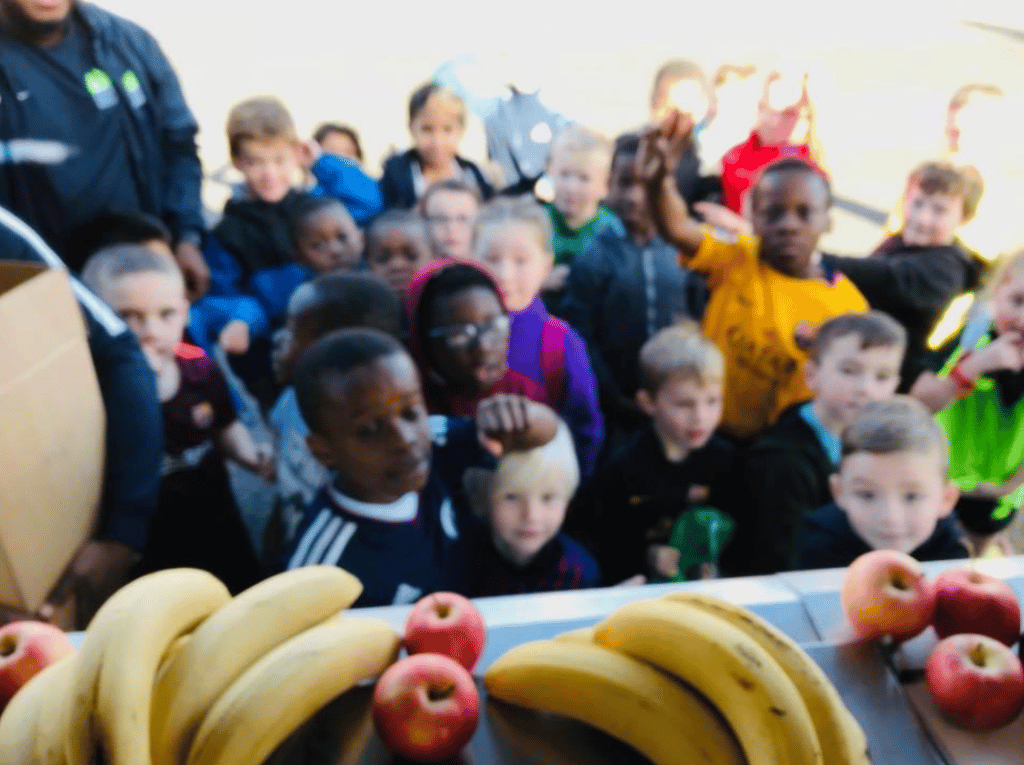 View from a food truck where excited young children queue for food and fruit.