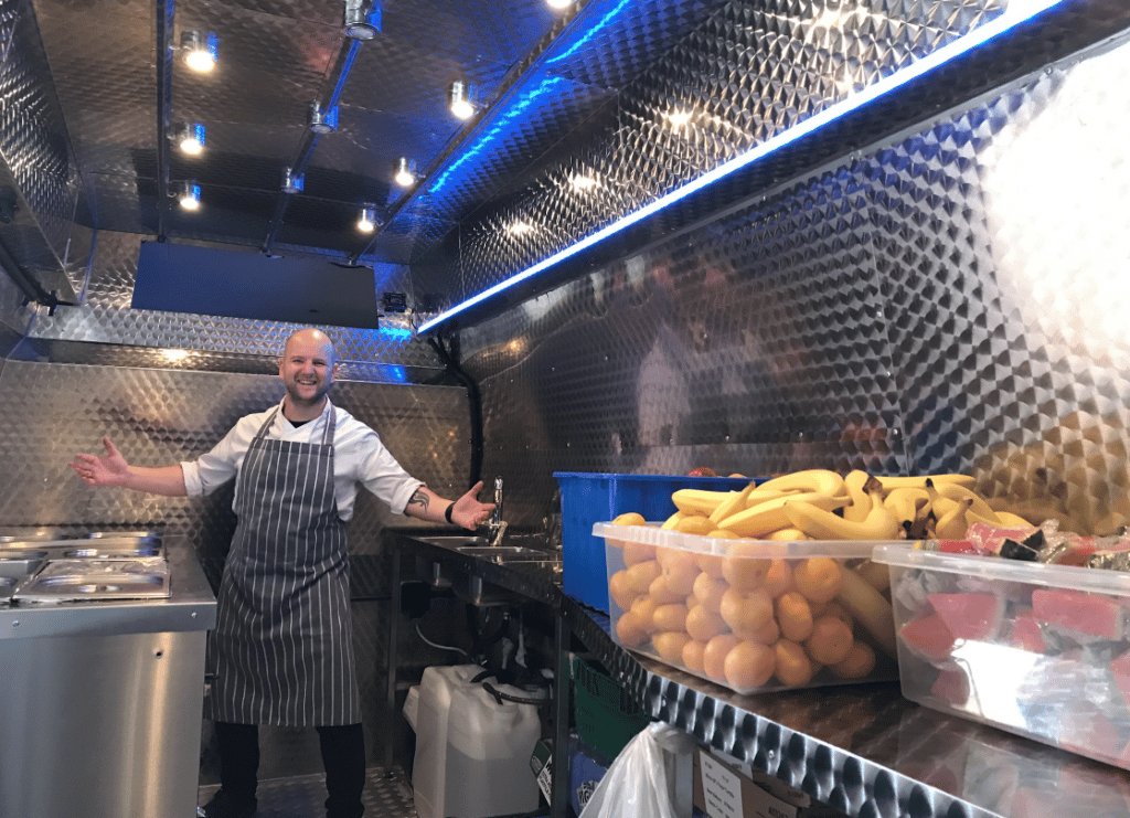 Chef Kevin at work inside the food truck with a big box of fresh fruit beside him
