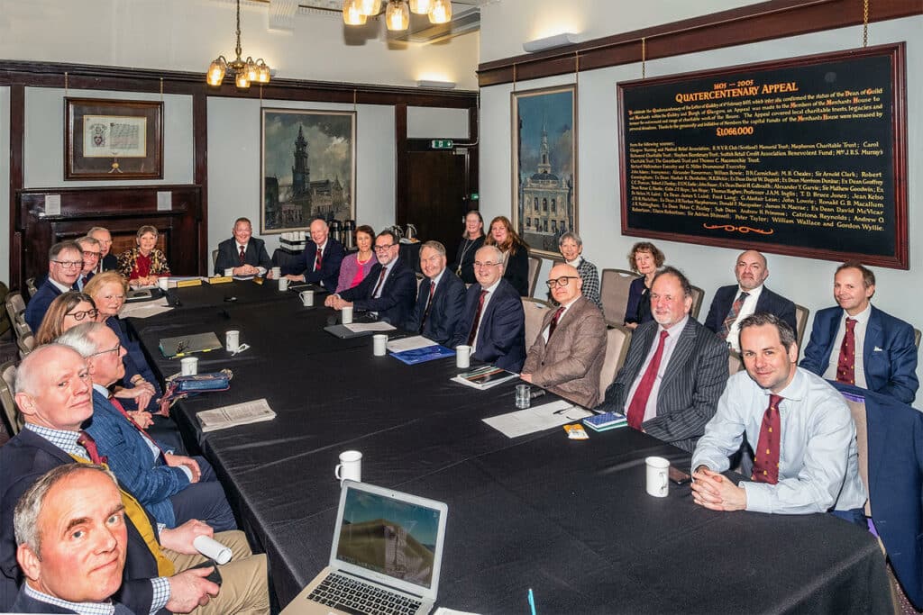 A group of Directors meet around a large table in the Merchants House of Glasgow