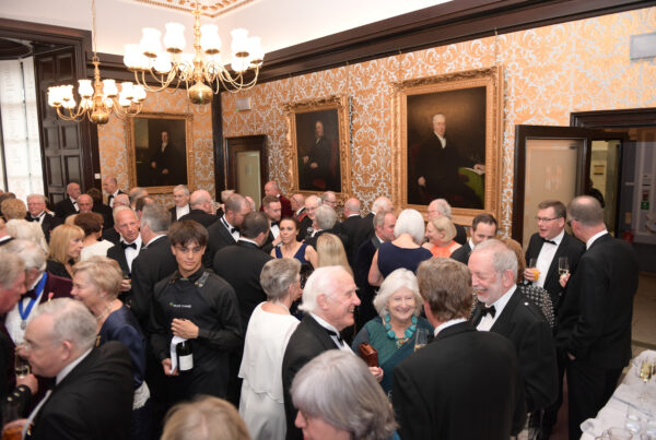 Members of the Merchants House enjoy a drink and socialising, all wear formal attire.