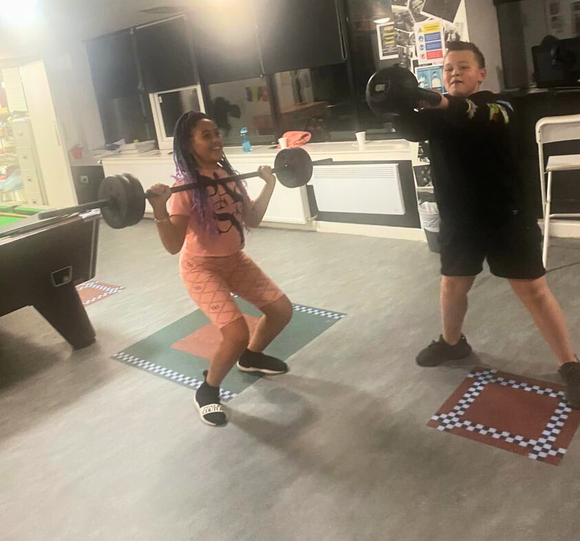 a teenager boy and girl lifting weights and exercising in a gym